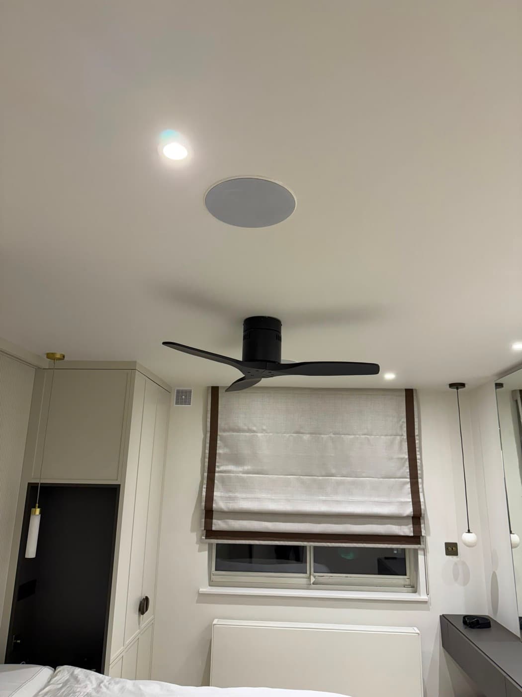 Bedroom with a black ceiling fan, downlights, a flush ceiling speaker and bedside lights