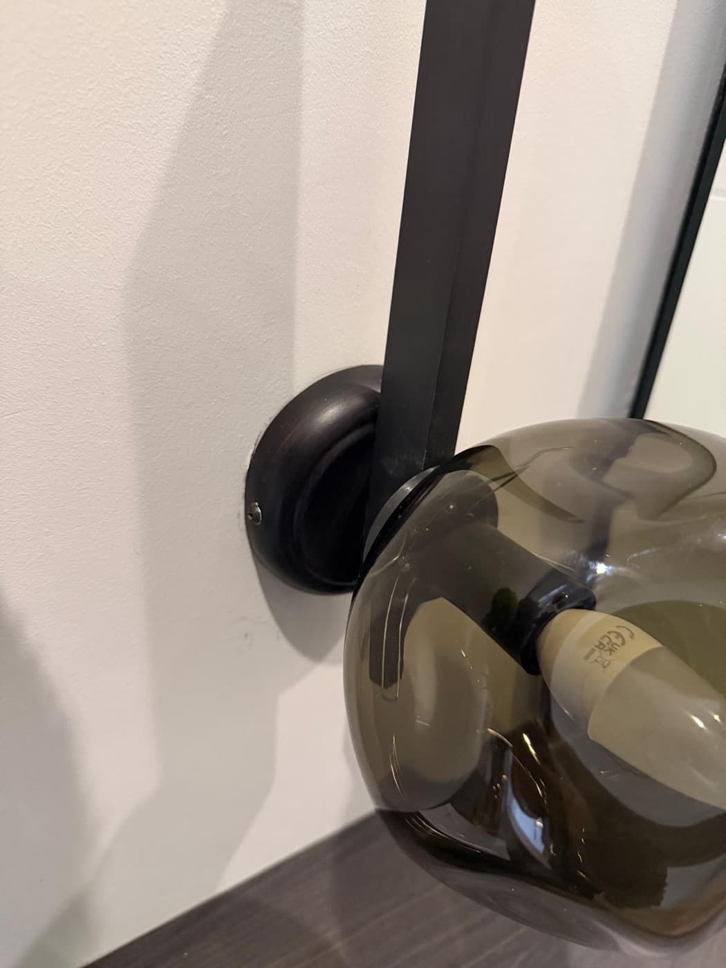 Smoked glass shade on a black wall-mounted light arm